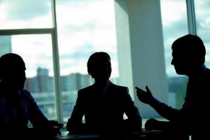 Three silhouetted business people in a room