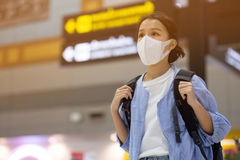 Young female traveller at airport with facemask