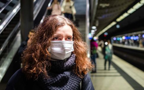 Woman wearing face mask on train station to protect from coronavirus