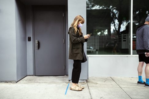 Woman waiting in queue with facemask to protect from COVID-19
