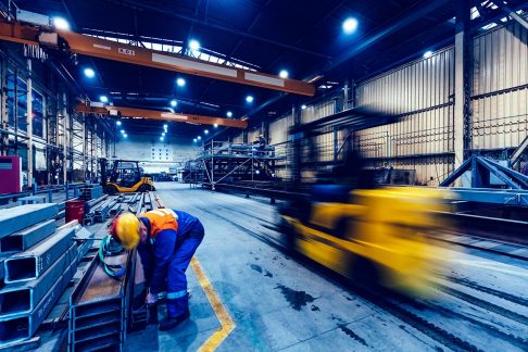 Steel worker in factory bending over