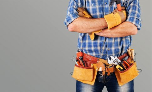 Handyman wearing tool belt with crossed arms