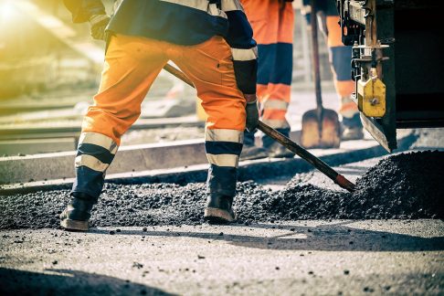 Construction workers shovelling gravel at a train line