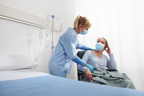 nurse take comfort elderly woman in wheelchair wearing surgical protective medical masks in hospital room, concept of isolation from corona virus covid 19