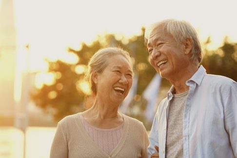 An older Asian couple laughing outdoors