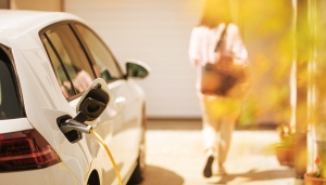 Woman walking into her home leaving her electric vehicle to charge